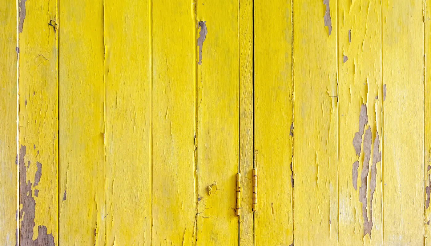 Yellow, weathered wooden planks; paint peeling to reveal wood grain.