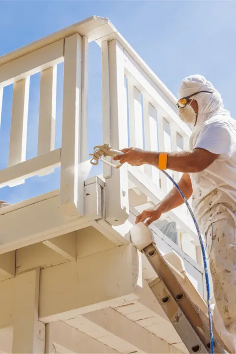 A painter spraying a timber deck