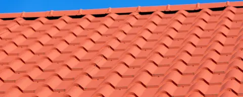 Terracotta roof tiles against a blue sky